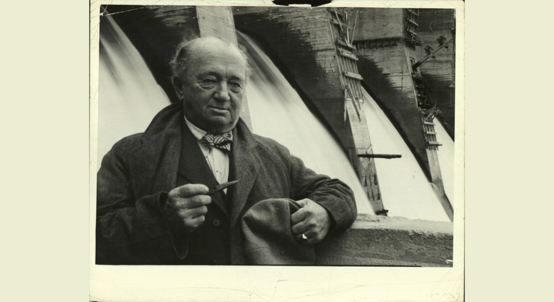 American Engineer Col. Huge Cooper, the chief consultant for the construction of Russia's Dnieper Dam. Holding pipe as he poses before the dam's spillway, 1931