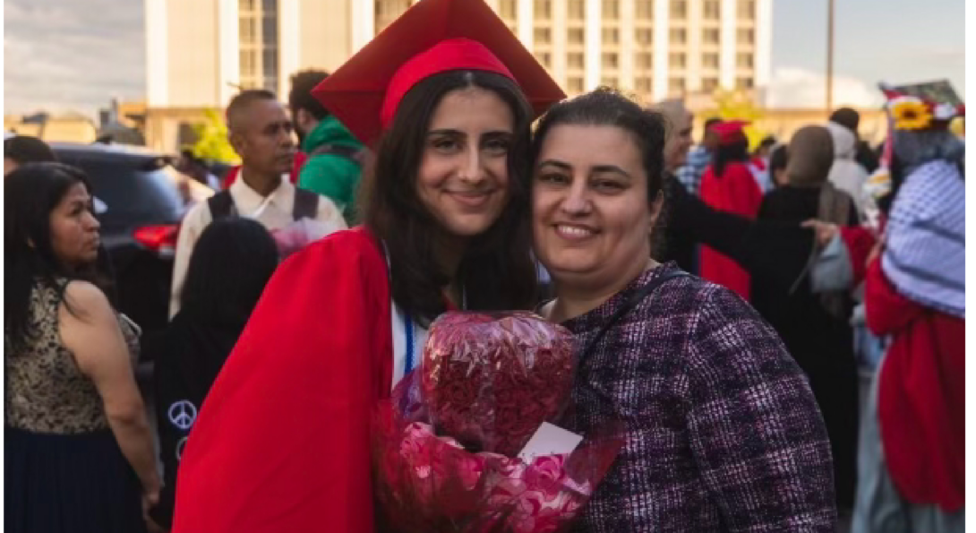 Lauren, dressed in red cap and gown, smiles while embracing her mother.