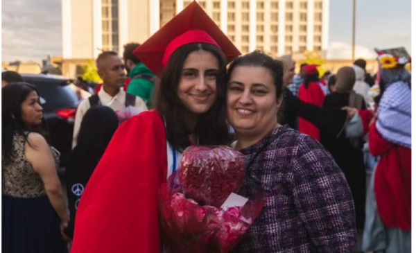 Lauren, dressed in red cap and gown, smiles while embracing her mother.